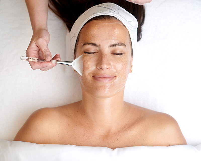 Frau mit geschlossenen Augen bekommt eine Dermalogica Pro Skin-Gesichtsbehandlung. Ihr Gesicht wird mit einem Pinsel berührt.